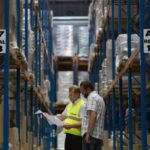 Supply Chain Managerowie podczas pracy w nowoczesnym magazynie logistycznym, kontrolujący i optymalizujący procesy zarządzania łańcuchem dostaw