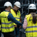 Zespół Nedcon Silesia w sprzęcie ochronnym (kaski, kamizelki odblaskowe) podczas szkolenia lub nadzoru w magazynie, podkreślając znaczenie bezpieczeństwa i zasad BHP