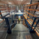 Widok magazynowej platformy składowania z regałami i schodami, obrazujący zintegrowany system składowania, który odgrywa kluczową rolę w efektywności i optymalizacji procesów logistycznych w łańcuchu dostaw - rozwiązania Nedcon