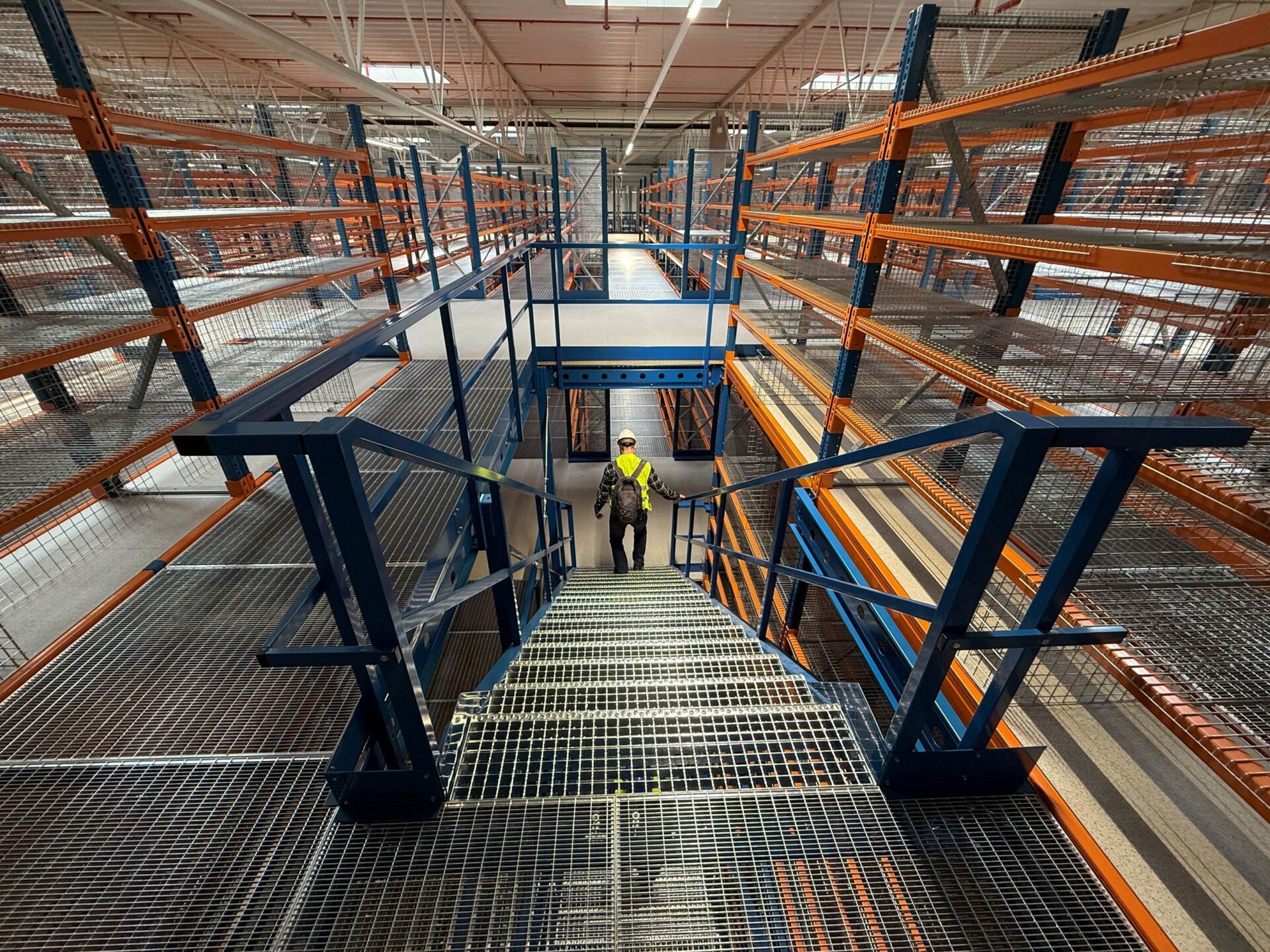 Widok magazynowej platformy składowania z regałami i schodami, obrazujący zintegrowany system składowania, który odgrywa kluczową rolę w efektywności i optymalizacji procesów logistycznych w łańcuchu dostaw - rozwiązania Nedcon
