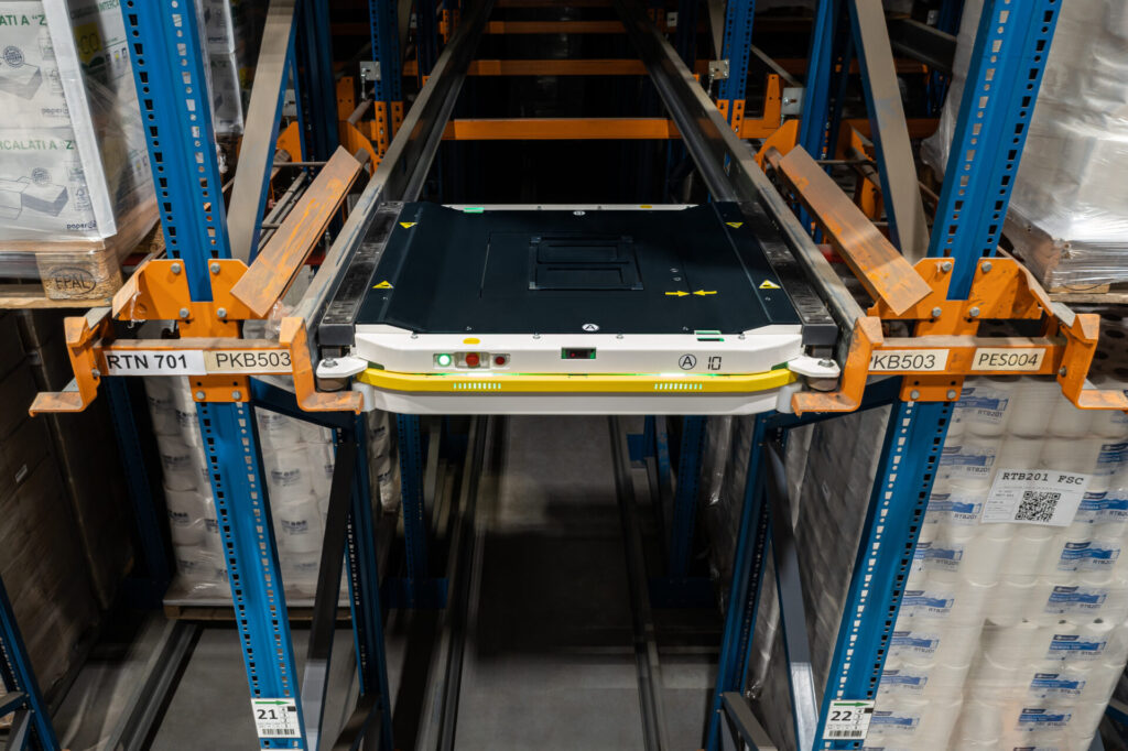 Zautomatyzowany system regałów wjezdnych typu Pallet Shuttle, gdzie wózek satelitarny transportuje paletę w głąb kanału składowania.