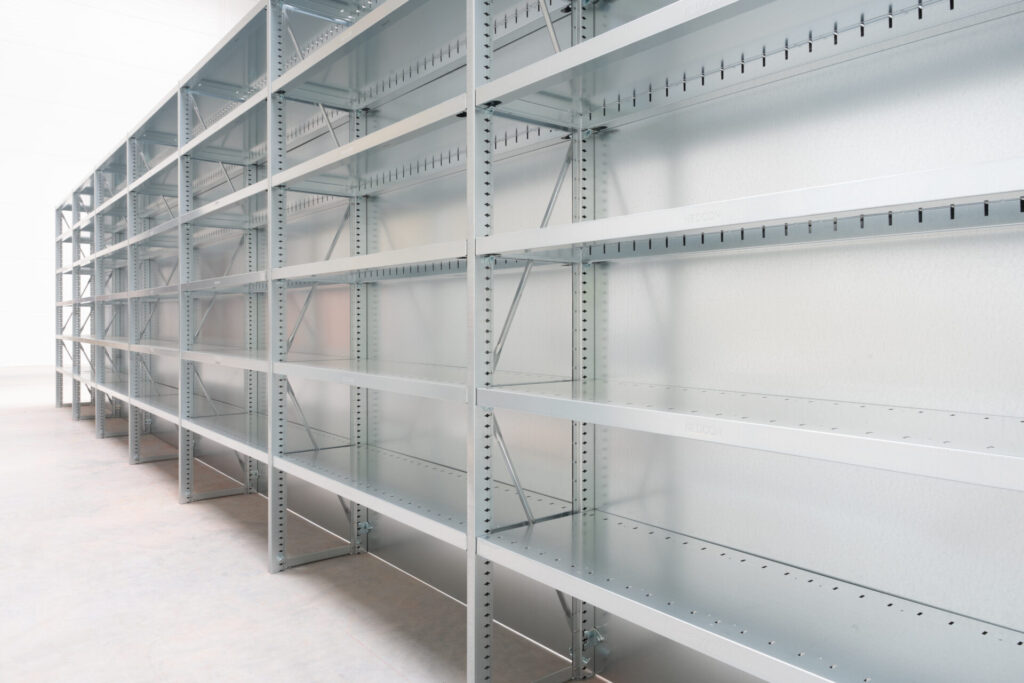 System regałów półkowych zintegrowanych z regałami rzędowymi w magazynie wysokiego składowania.