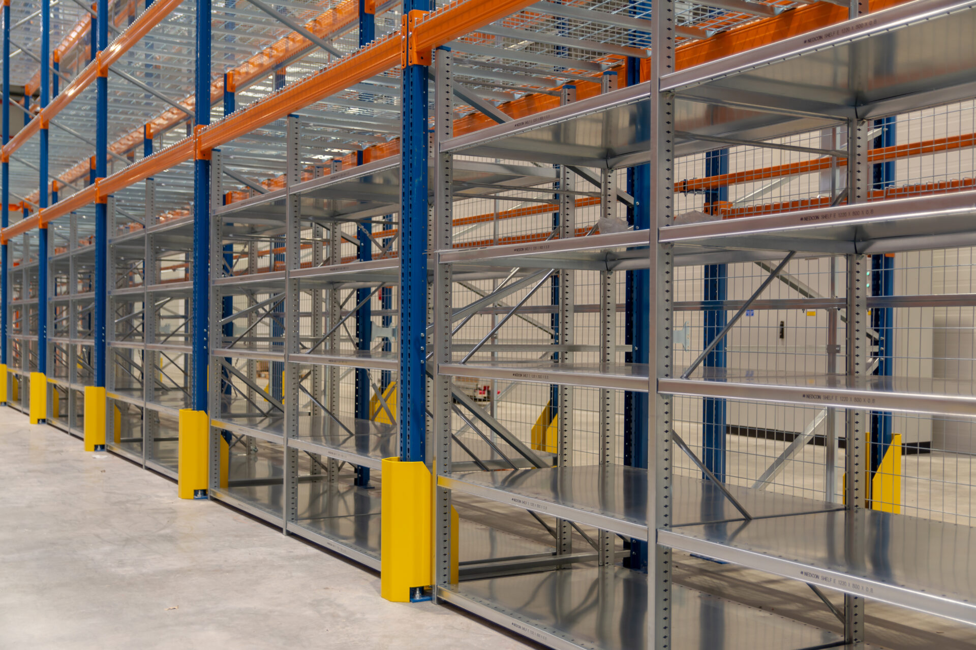 Metalowe regały półkowe z regulowanymi półkami w pustej przestrzeni magazynowej.