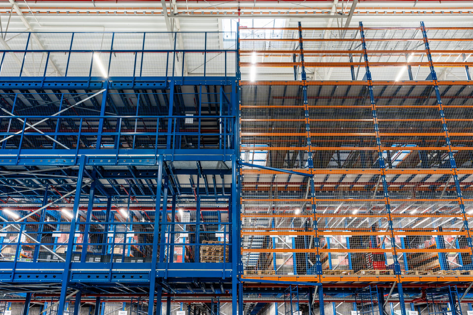 Metalowe regały wysokiego składowania w hali magazynowej e-commerce, wspierającej logistykę i kompletację zamówień online